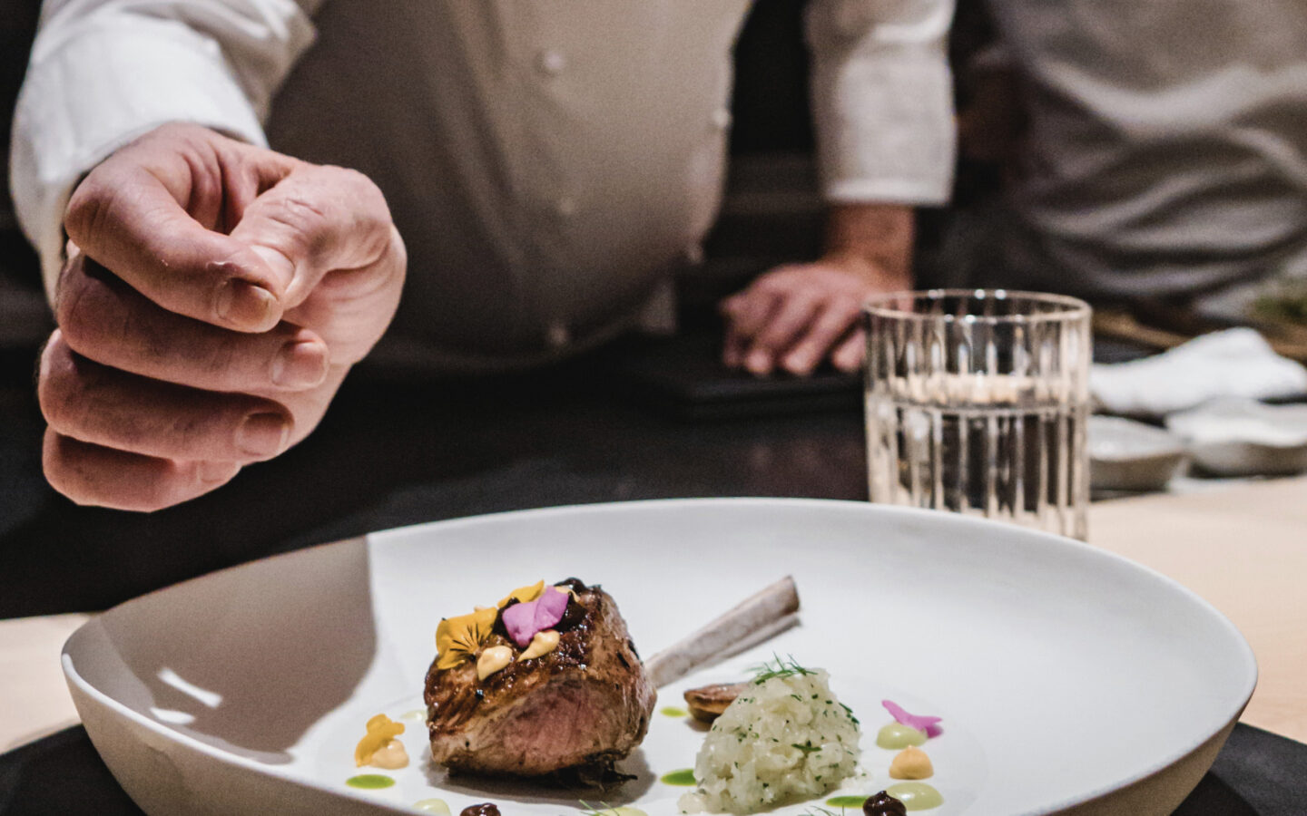 LSL chef Leroy finishing a dish of lamb with jalapeño sauce, Japanese black garlic, mustard, honeysuckle flowers.
