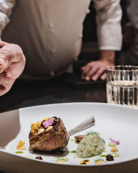 LSL chef Leroy finishing a dish of lamb with jalapeño sauce, Japanese black garlic, mustard, honeysuckle flowers.